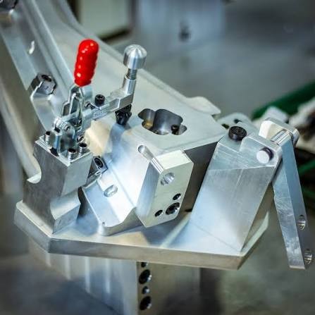 Machined aluminum fixture with toggle clamps holding a part
